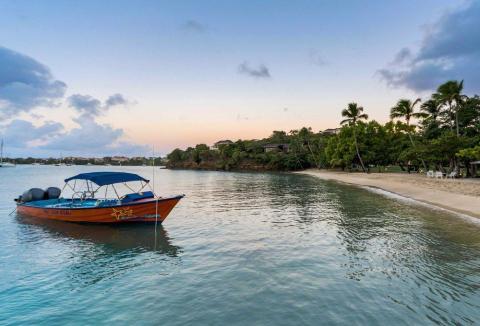 Orange boat CG 6148 on calm beach at dusk with palm trees and resort background