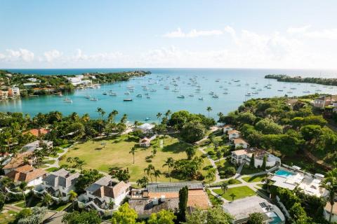 Sailboats in a serene, affluent coastal neighborhood with lush greenery.