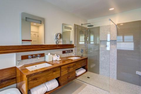 Modern bathroom with wooden vanity, mirrors, and walk-in shower
