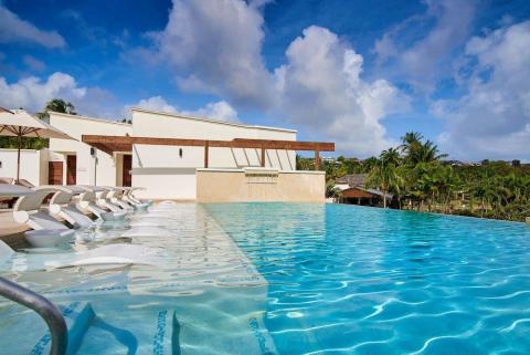 Luxury resort pool with submerged lounge chairs and tropical backdrop