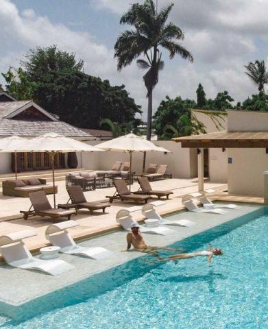 Luxurious resort pool with loungers, umbrellas, and palm trees, perfect for relaxation.