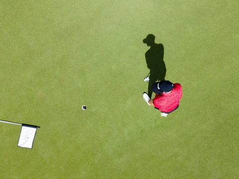 Cayman Tourism Board Precision on the Green: A Golfer The image depicts an aerial view of a golfer on a putting green