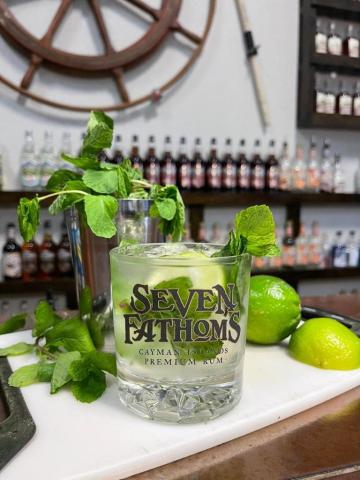 Cayman Tourism Board Tropical Rum Cocktail Experience in a Maritime-Themed Bar This image features a glass of what appears to be a cocktail, prominently garnished with fresh mint leaves