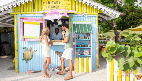 Cayman Tourism Board Colorful Conversations at Heritage Kitchen: A Tropical Beachfront Food Stand In the image, you see a colorful beachfront food stand named "Heritage Kitchen
