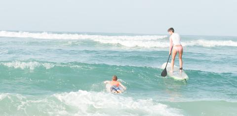 Cayman Tourism Board Ocean Adventures: Surfboarding and Stand-Up Paddleboarding in Emerald Waves This image shows two individuals engaged in water sports at the ocean