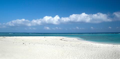 Cayman Tourism Board Serene Shoreline: Turquoise Tranquility This image shows a beautiful beach scene under a clear blue sky, scattered with a few clouds