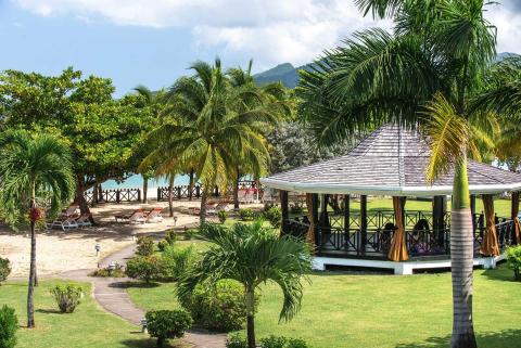 Serene tropical beach gazebo with palm trees, sandy shore, and mountain views