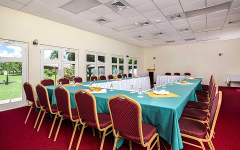 Banquet hall setup with U-shaped table, green cloths, and red chairs for event.
