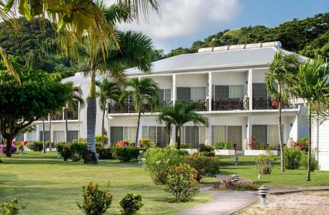 Tropical resort hotel with gabled roof, palm trees, and lush greenery