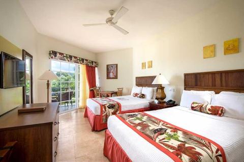 Bright twin hotel room with tropical decor and greenery view