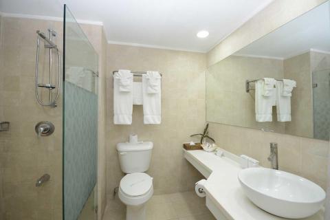 Modern bathroom with glass shower, vessel sink, and beige tiles.