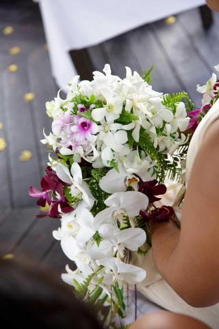 Bridal bouquet with white orchids and purple flowers at a wedding.