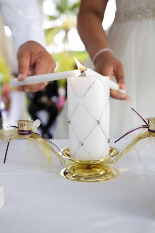 Bride and groom lighting unity candle at outdoor wedding ceremony