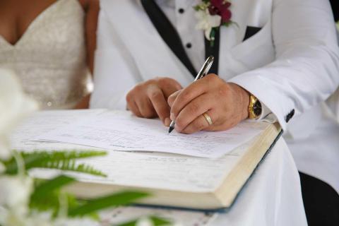 Bridegroom signing marriage certificate at wedding