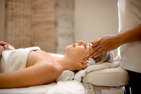 Relaxed woman receiving facial massage in serene spa setting