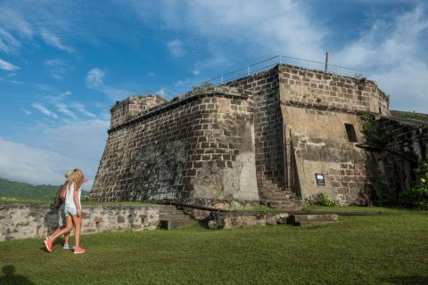 Historical Fortress Tour By Female Traveler On Sunny Day Woman walking towards ancient stone fortress on a sunny day