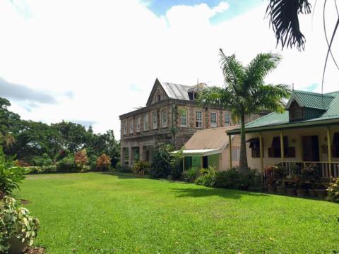 Historic Stone House And Modern Building In Lush Garden Historic stone two-story house and modern yellow cottage in lush garden setting