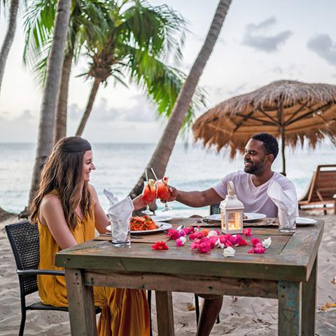 Romantic Beach Dinner For Couple At Sunset Romantic beach dinner for couple with sunset, lantern, and tropical drinks.