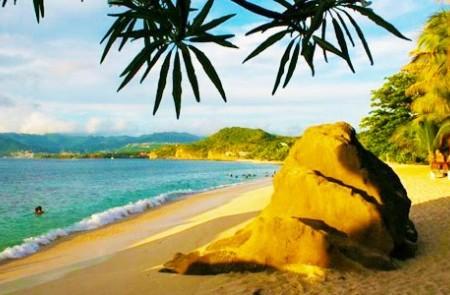Tropical Beach With Clear Blue Sea And Green Hills Tropical beach with clear blue sea, lush hills, and palm leaves framing the sunny sky.