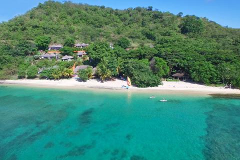 Secluded Tropical Beach With Water Sports And Nature Tropical beach with turquoise waters, paddleboarders, and lush hills