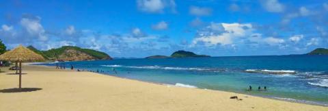 Serene Tropical Beach Scene With Thatched Umbrella Scenic tropical beach with people, thatched umbrella, and calm blue waters