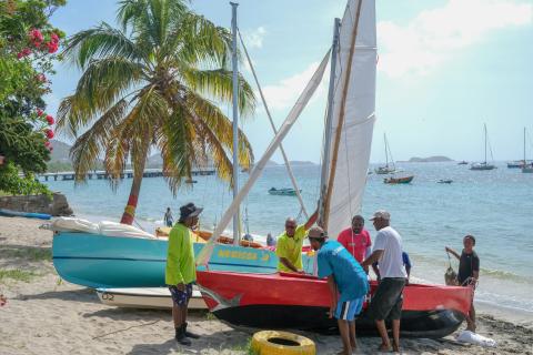 Launching Nerissa Ja Sailboat At Tropical Beach Group launching colorful sailboat