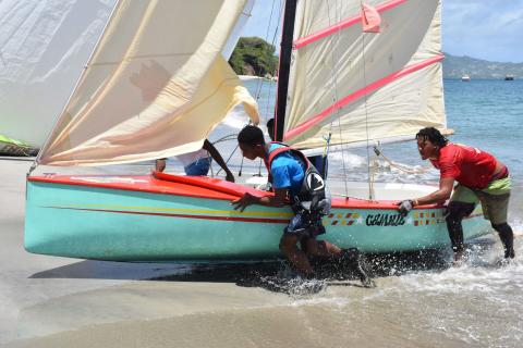 Team Launching Cool Breeze Sailboat On Sunny Beach Team launching
