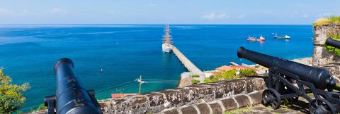 Coastal Historic Fort View With Cannons And Tall Ship Scenic coastal view from historic fort with old cannons overlooking ocean and tall ship.