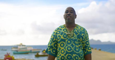 Man In Colorful Shirt On Tropical Beach With Boats Middle-aged man on beach with calm sea and boats in background