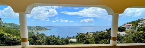 Scenic Coastal View From Balcony Overlooking Bay Scenic coastal view from balcony with boats, homes, and lush greenery under clear skies.