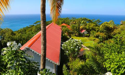 Tropical Beach Landscape With Colorful Villas And Ocean Tropical landscape with ocean view, greenery, and red-roofed cottages under palm trees