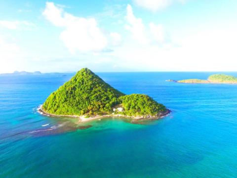 Tropical Cone-Shaped Island Aerial View Aerial view of a lush cone-shaped island with turquoise waters and a small beach