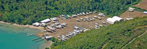 Marina Aerial View With Boats And Lush Shoreline Aerial view of marina with boats at pier and on land surrounded by forest and sea.