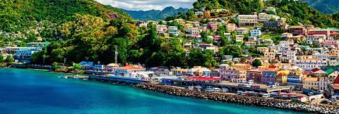 Colorful Coastal Town With Busy Port And Lush Hills Colorful coastal town with port, vibrant homes, and busy waterfront road.