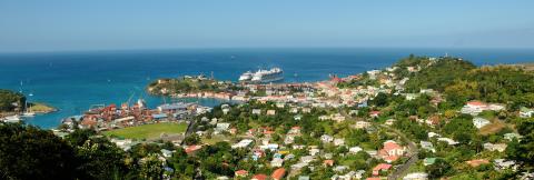Bustling Coastal Town With Harbor And Cruise Ships Panoramic view of vibrant coastal town with harbor and lush green hills.