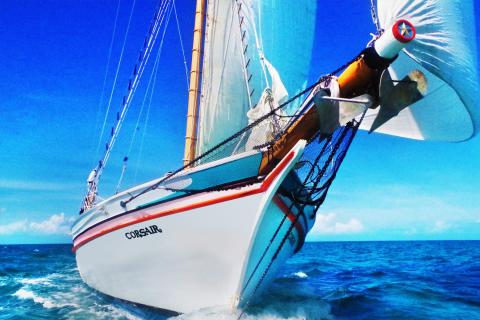 Sailing Adventure On Corsair In Blue Ocean Sailing boat Corsair heeling in vibrant blue ocean with full sails and clear skies