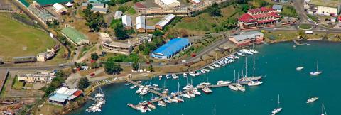 Vibrant Coastal Marina Scene With Boats And Buildings Vibrant coastal marina scene with docks, boats, and adjacent athletic field