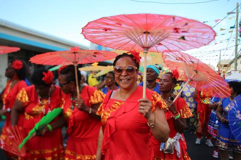 Festive Parade With Colorful Costumes And Umbrellas Smiling woman in red at festive parade with colorful umbrellas and flowers.