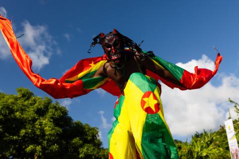 Festive Pan-African Costume And Mask In Carnival Person in colorful costume with red mask at outdoor cultural festival