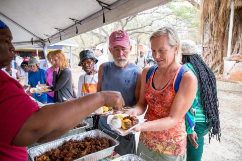 Community Outdoor Catering Event With Food Serving Outdoor food catering scene with server in red and people selecting meals