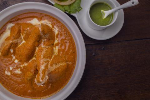 Authentic Butter Chicken With Chutney On Wooden Table Delicious butter chicken curry with green chutney on rustic wooden table