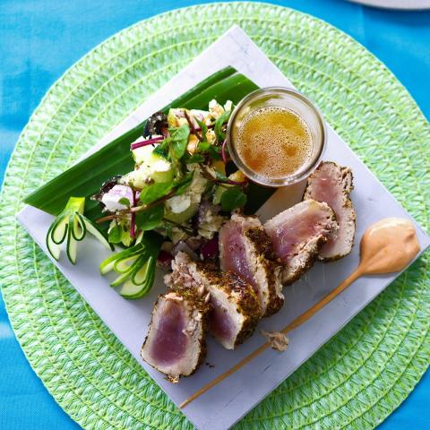 Seared Tuna Steak Dinner With Salad And Beer Seared tuna steak dinner with salad, feta, and beer on a square plate.