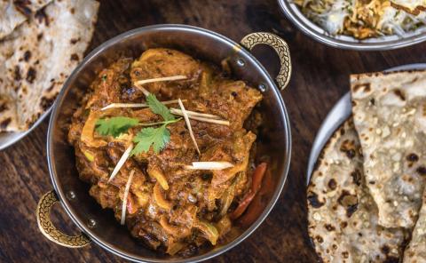 Indian Curry With Naan And Biryani Dish Indian curry with naan and biryani in metal bowls, garnished with herbs.