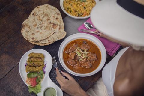 Indian Cuisine Feast With Naan, Kebabs, And Biryani Indian feast with naan, seekh kebabs, mutton curry, and biryani on a table.