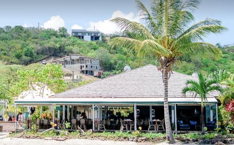 Beachside Restaurant In Tropical Setting Tropical beachside restaurant with palm trees and scenic hillside view.