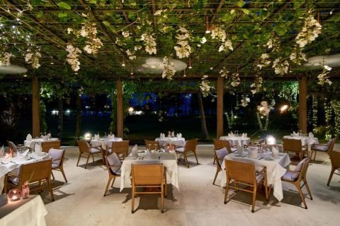 Elegant Outdoor Dining Area With Pergola And Lights Outdoor evening dining setup under pergola with string lights and white decor.
