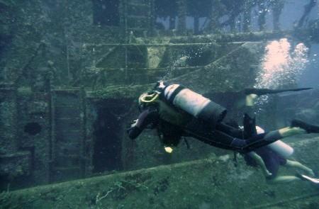 Scuba Diver Explores Sunken Shipwreck Underwater Scuba diver explores sunken shipwreck with light beam illuminating scene