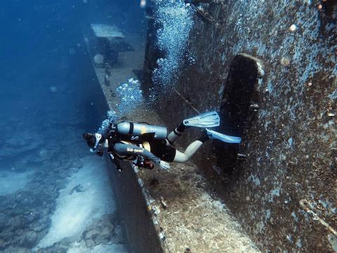 Scuba Diver Explores Eerie Sunken Shipwreck Scuba diver explores eerie, algae-covered sunken ship in underwater adventure.