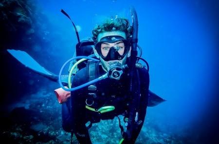 Scuba Diver Exploring Murky Underwater Reef Scuba diver in full gear explores murky underwater scene