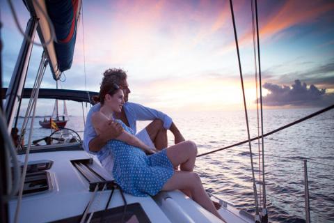 Romantic Sunset Sailing Couple On Calm Sea Couple enjoying sunset on sailboat with serene ocean backdrop
